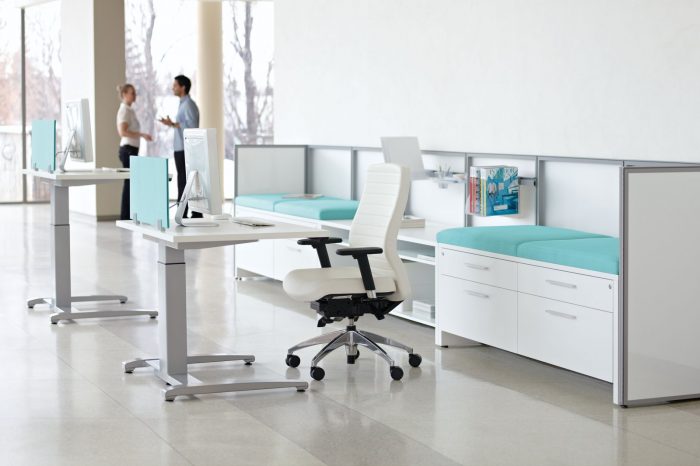 Studio shot of a medium backed Aspen office chair placed at a workstation. Cabinets and work station is placed against the wall.