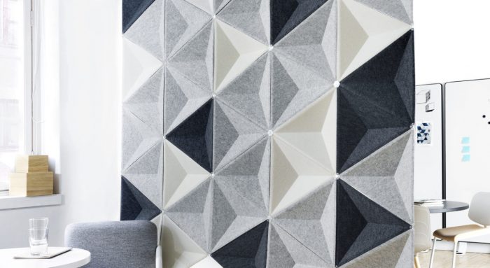 Studio shot of Aircone acoustics formed into a privacy wall. Three different colored pieces are used. There are two sets of chairs and tables broken up by this partition.
