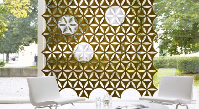 Studio shot of olive colored Airflake acoustics hung along the outer wall of the lobby. Two white chairs are placed across a glass table from one another.