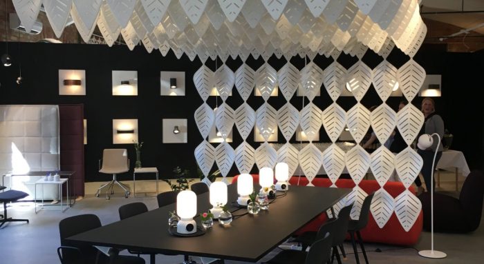 Interior photograph of Airleaf acoustics along the ceiling of a dining area. Additional Airleaf's form a wall just behind the head seat at the table. A red couch is placed just behind it, facing the back wall.