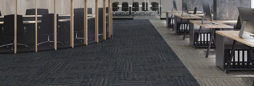 Studio shot looking from the front, into an open office area. Outfitter carpeting lines the whole area. To the left a round glassed in conference room is set up.