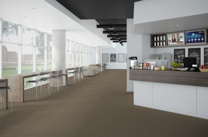 Passages flooring inside a cafe. The counter is on one side, with two fruit bowls by the cash register. Tall backed chairs are placed in front of seating that goes all along the front window.