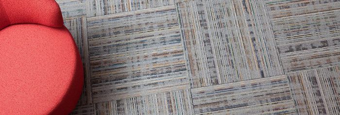 Studio shot of a red cushioned chair, resting atop Relativity carpeting. Each square was given a quarter turn.