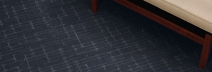 Studio shot of a wooden framed couch resting on top of Tempo carpeting.