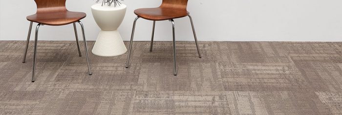 Studio shot of Well Versed model carpet, in a guest area. At the side are two chairs, with a round end table between. A wire sculpture rests on top.