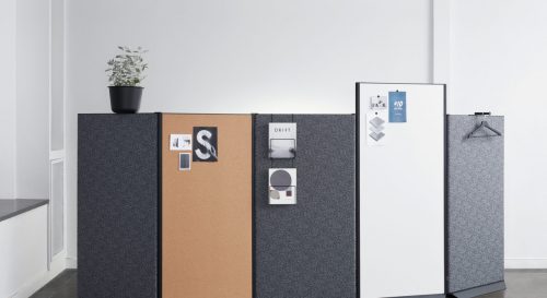 Studio shot of dB privacy screens along the corner of the open office. Each screen is a diffrent height and color, with cards, notes and coat hangers all along this partition.